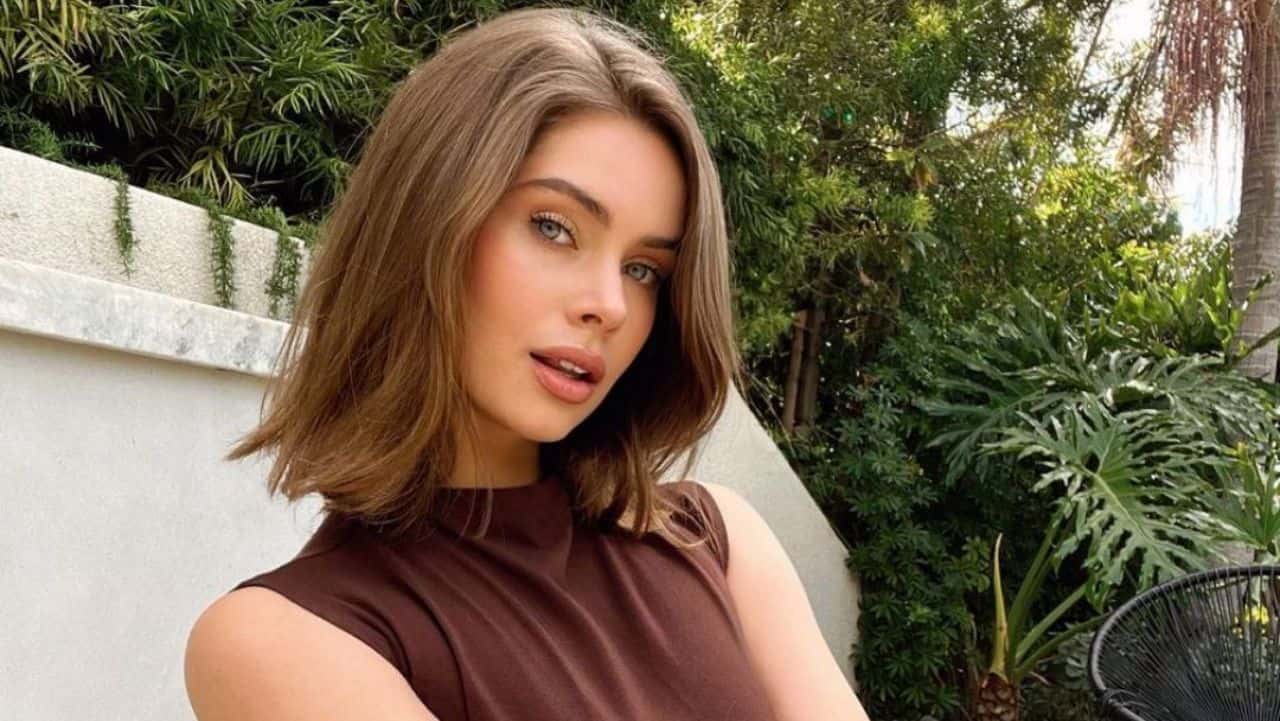 Brandy Gordon embraces a minimalist chic aesthetic, pairing a sleeveless brown mock-neck top with an effortlessly styled lob for the perfect natural daytime look.