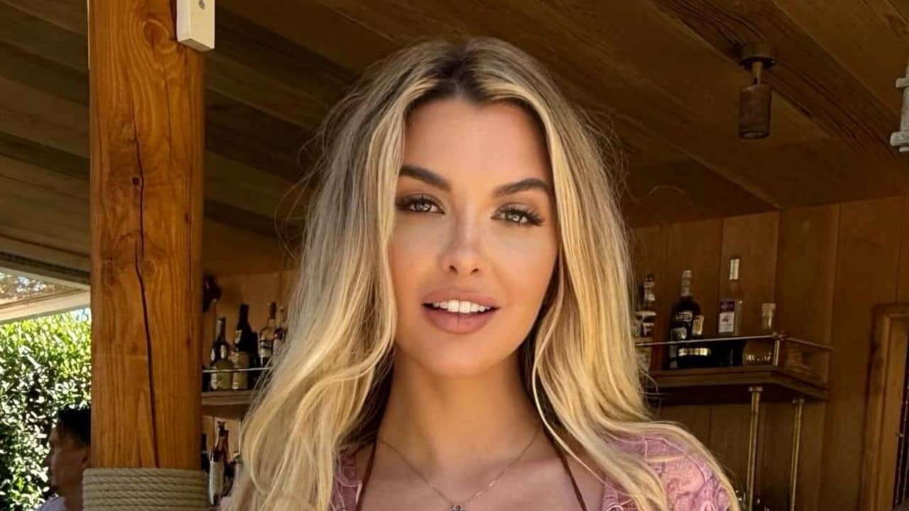 With a defined eye look and her signature warm blonde highlights, Emily Sears showcases a touch of modern glamour in her delicate pink lace top that is both approachable and stylish.